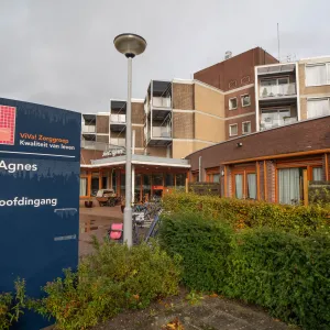De ingang van ViVa! Zorggroep Sint Agnes met een bord en een duidelijk pad richting de hoofdingang, omringd door groene begroeiing en fietsstallingen.