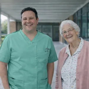 Medewerker staat lachend buiten met cliënt