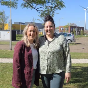 Twee Verzorgenden IG staan lachend naast elkaar buiten 