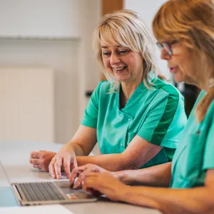 Ingrid achter laptop samen met collega in bedrijfskleding