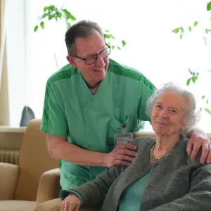 Cliënt lacht in huiskamer samen met medewerker van ViVa! Zorggroep