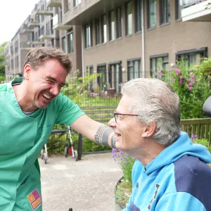 Zorgmedewerker ViVa! de Boogaert lacht samen met cliënt in de tuin