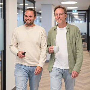 Twee collega's lopen lachend door de gang naar overleg