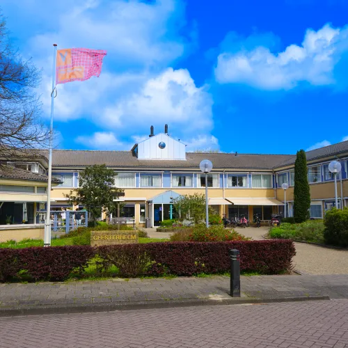 Vooraanzicht van woonzorglocatie Geesterheem met ViVa!-vlag in de tuin bij ViVa! Zorggroep