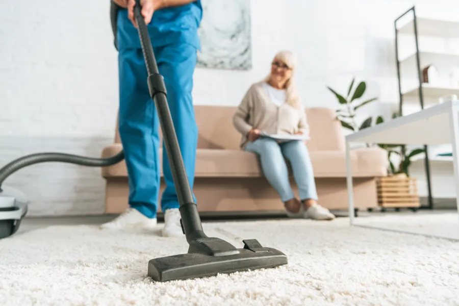 Thuishulp stofzuigen met client op achtergrond