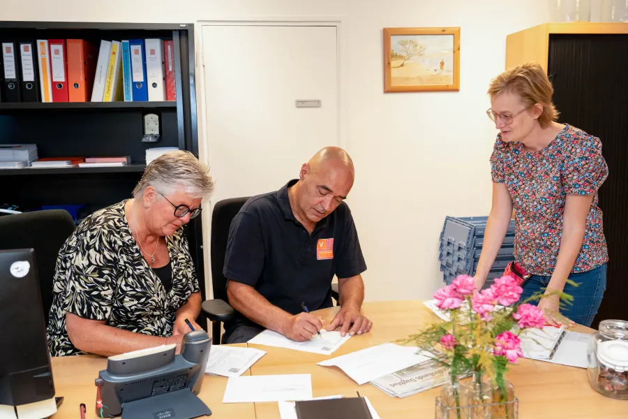 Drie collega’s bespreken documenten op kantoor bij ViVa! Zorggroep