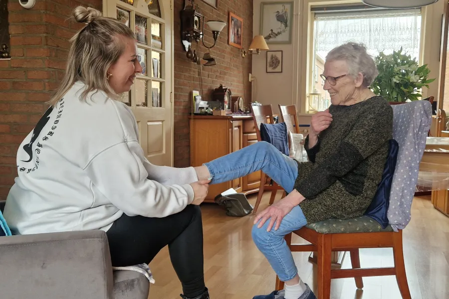 ADL medewerker doet steunkousen aan bij patient