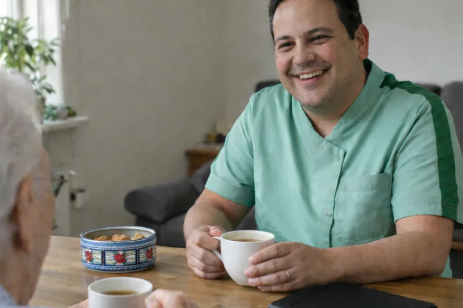 Medewerker in gesprek met cliënt aan de keukentafel
