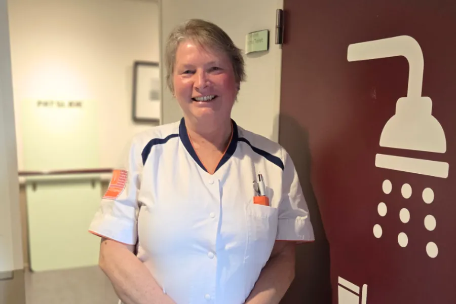 Collega staat in de gang van de revalidatie GRZ van ViVa! en lacht vriendelijk 