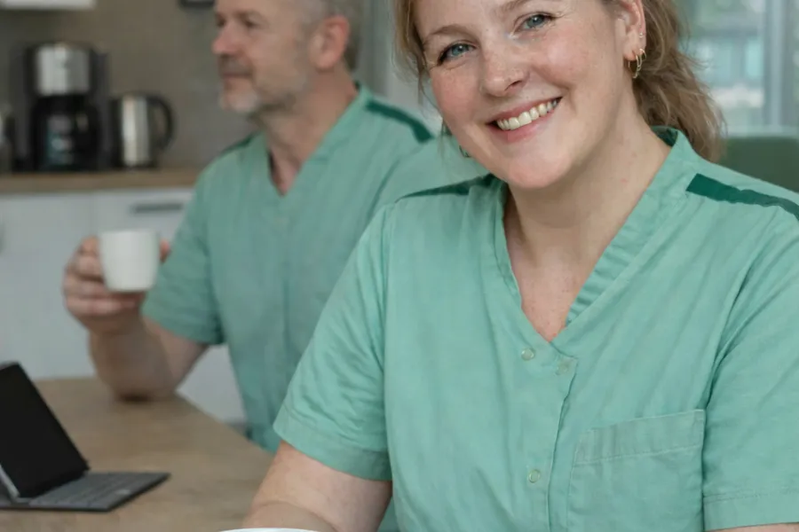 Verpleegkundige woonzorg met koffie en collega op achtergrond