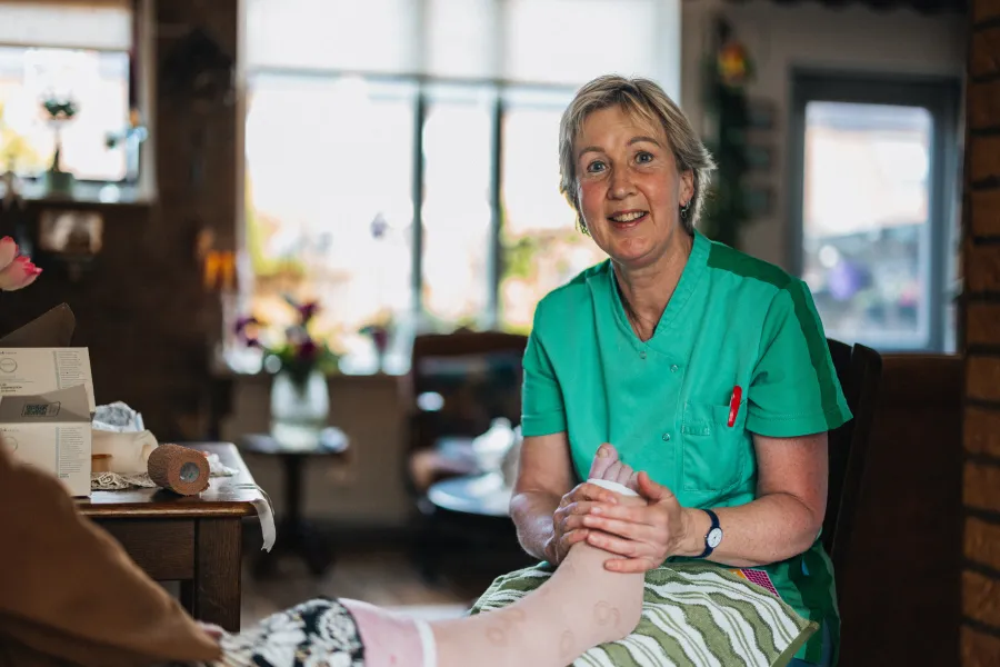 Elisabeth trekt steunkousen aan tijdens de wijkzorg