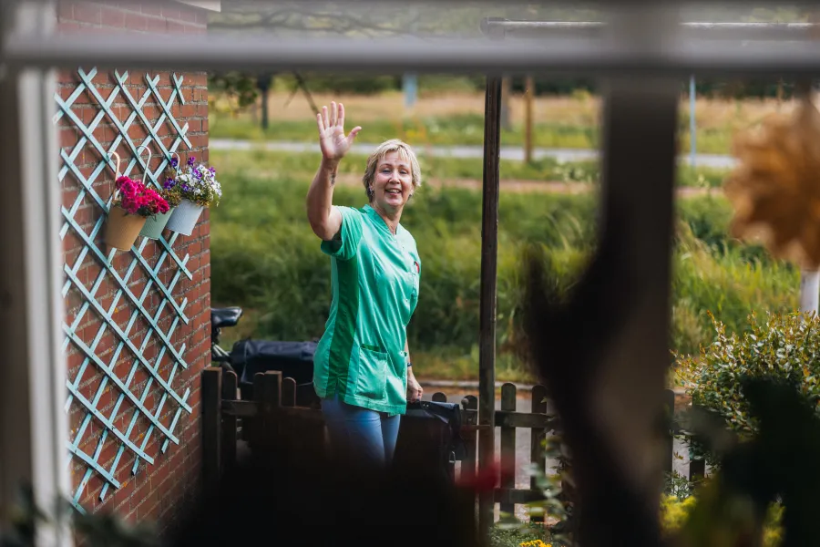 Elisabeth zwaait naar cliënt tijdens wijkzorg