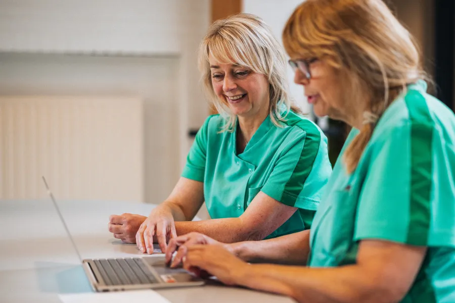 Ingrid achter laptop samen met collega in bedrijfskleding