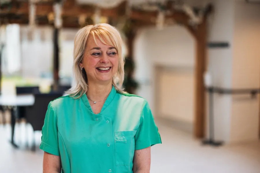 Ingrid lacht op gang van de woonzorg in bedrijfskleding